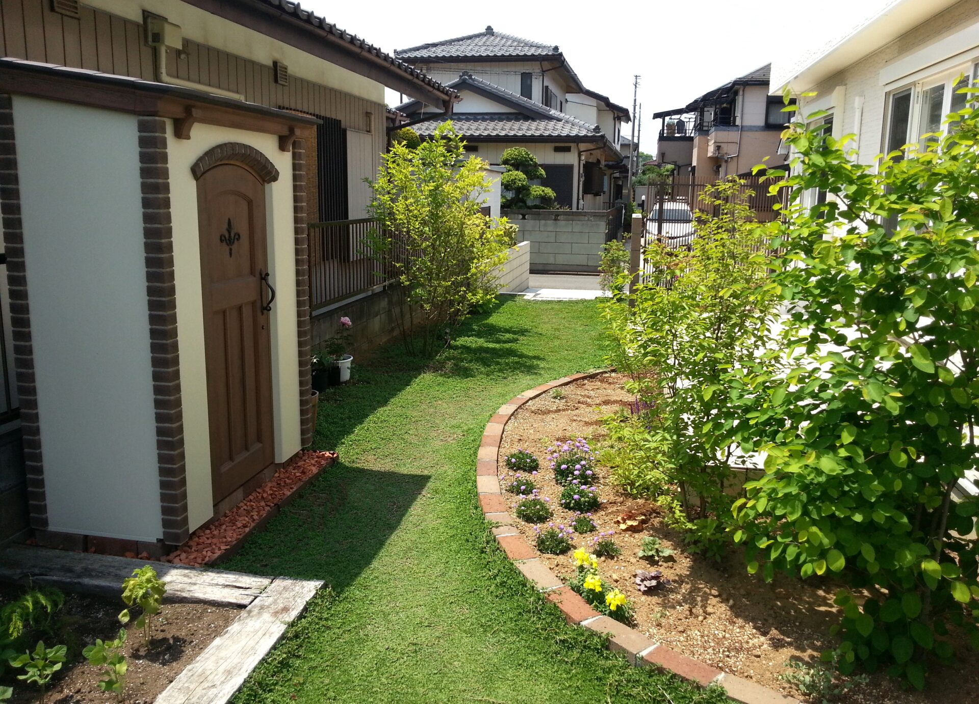 鴻巣市のスタイリッシュな外観と調和するナチュラルテイストな外構の物置、芝